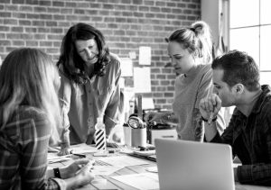 Group of professionals collaborating over documents in an office setting, representing teamwork in financial services or business strategy.